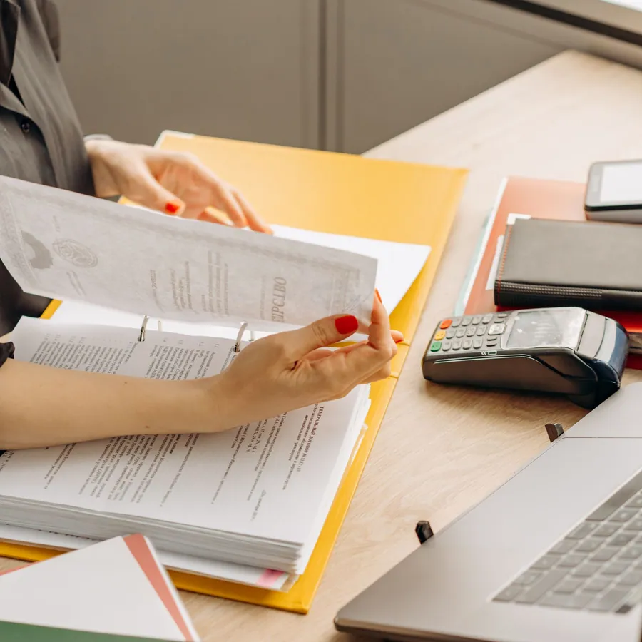 Profissional folheando documentos financeiros em uma mesa